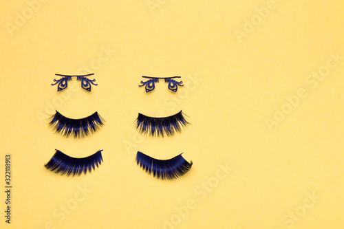 three pairs of different false eyelashes on a yellow background copy space top view, fluffy black eyelashes, butterfly-shaped eyelashes