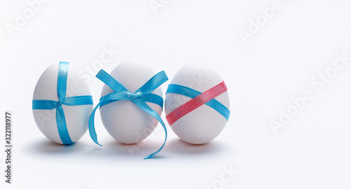 White eggs with blue ribbon on white background. Happy easter. New life concept. Holiday card. © Natali Illar