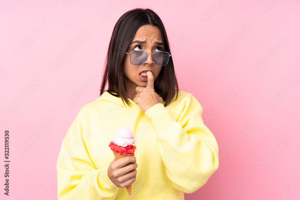 Young brunette girl holding a cornet ice cream over isolated pink background nervous and scared Young brunette girl holding a cornet ice cream over isolated pink background nervous and scared