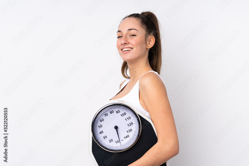 Young brunette woman over isolated white background with weighing machine Young brunette woman over isolated white background with weighing machine