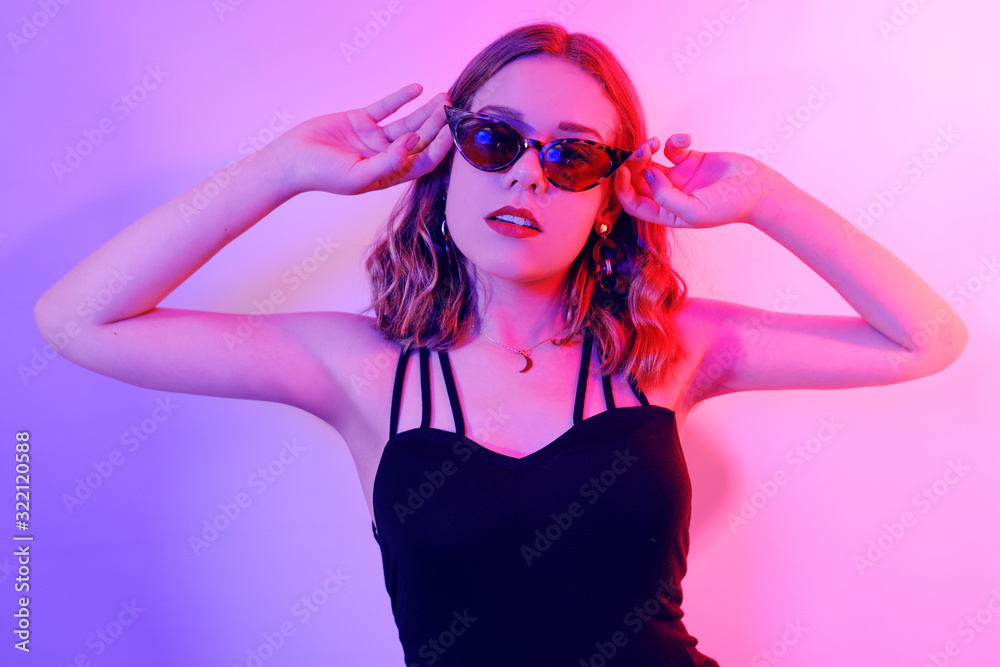 Beautiful girl in neon. Fashion photo of a short-haired girl, dancing, sun glasses. Girl in red and blue light posing. Beautiful girl in neon. Fashion photo of a short-haired girl, dancing, sun glasses. Girl in red and blue light posing.