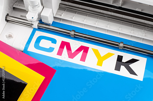 production making CMYK sticker with plotter cutting machine on cyan blue colored vinyl film. Advertising Industry diy design concept background.