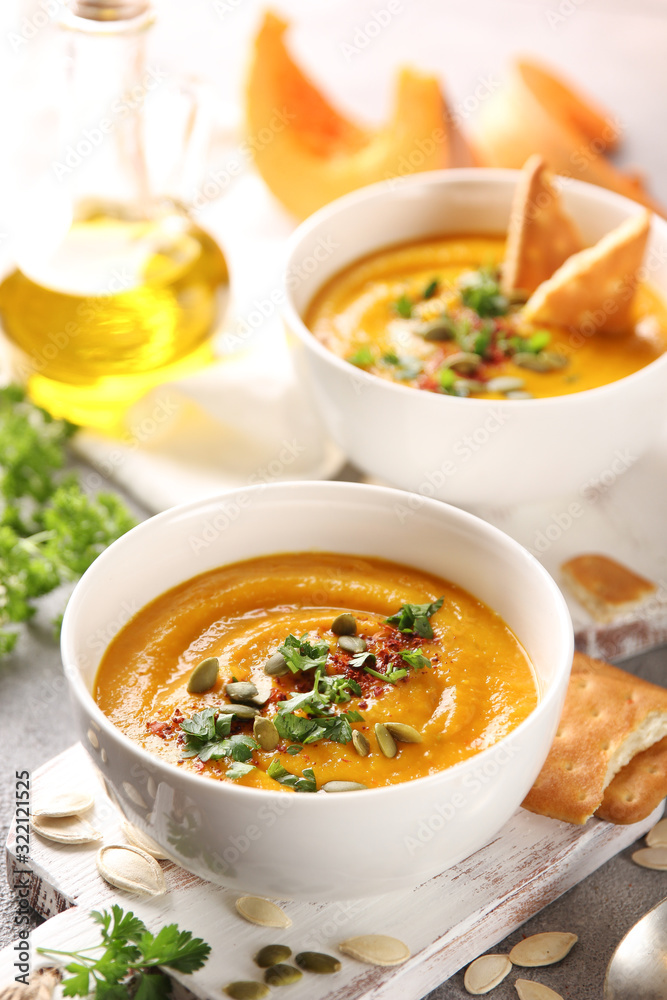Concept of Russian cuisine. Pumpkin cream soup with cookies on a light background. Pumpkins, olive oil, spices, spoon, pumpkin seeds, herbs. Background image, copy space Concept of Russian cuisine. Pumpkin cream soup with cookies on a light background. Pumpkins, olive oil, spices, spoon, pumpkin seeds, herbs. Background image, copy space