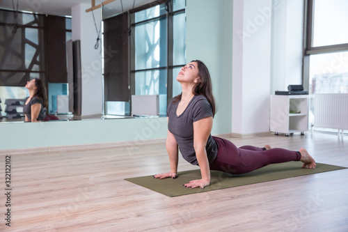 Photo of young woman practicing yoga indoor. Beautiful girl practice yoga in class. Yoga studio instructor. Blurred background.