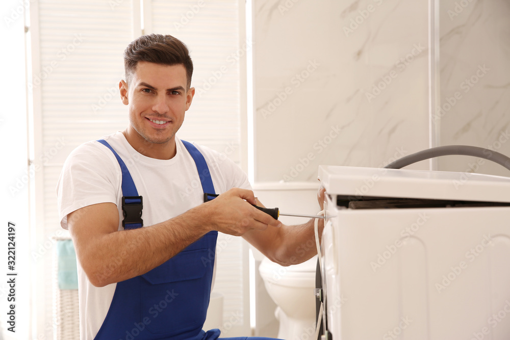 Professional plumber repairing washing machine in bathroom Professional plumber repairing washing machine in bathroom