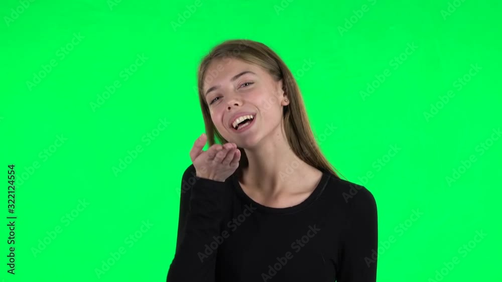 Young woman showing heart with fingers then blowing kiss. Green screen