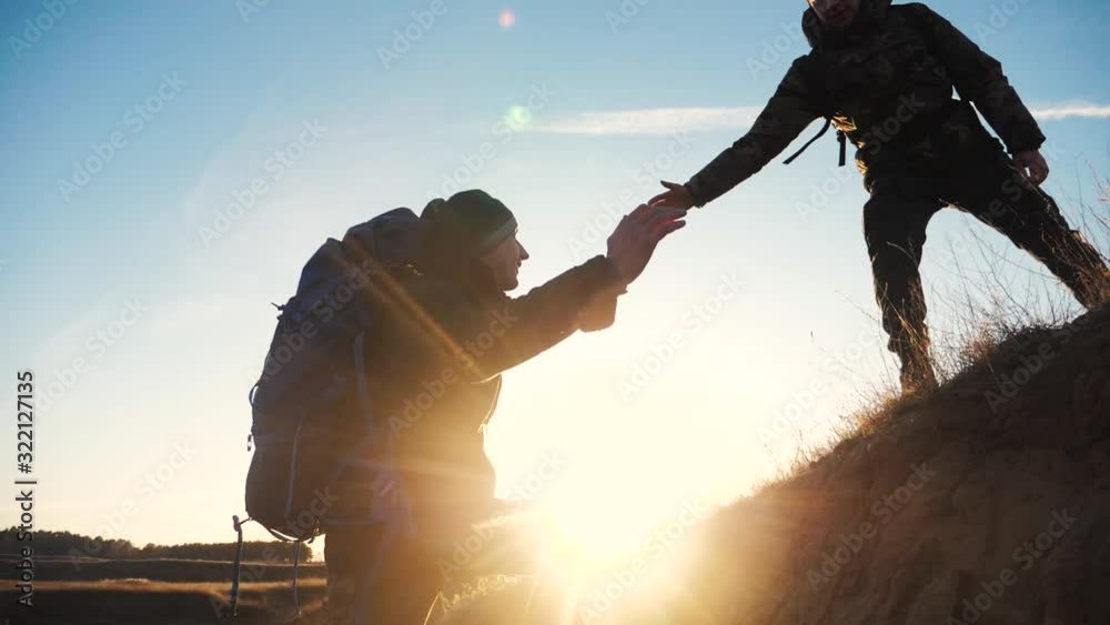 teamwork two men help helping hand business travel silhouette concept. two tourists lends a helping hand climb the cliffs mountains. people climbers climb to top teamwork overcoming hardships the path