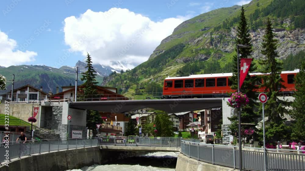 Red train in Zermatt, luxury alpine ski resort town. Scenic railway across Swiss Alps to Matterhorn mountain. Switzerland summer tourism destination, 4k.