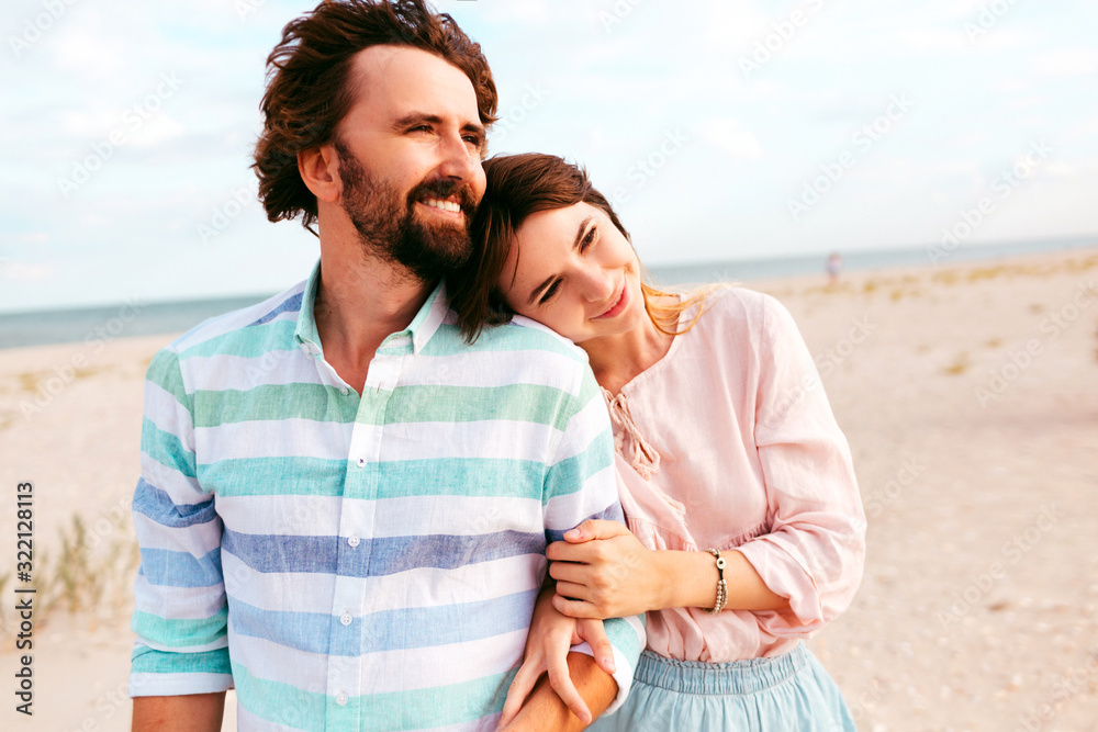 Beach couple walking on romantic travel honeymoon vacation summer holidays romance. Young happy lovers, Multiracial woman and Caucasian man holding hands embracing outdoors