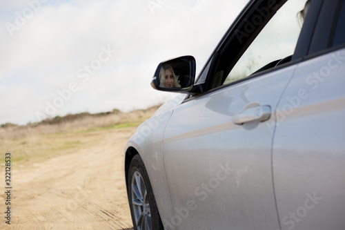 closeup of young blond woman driving auto outdoor wearing grey coat at fall day © Вероника Зеленина