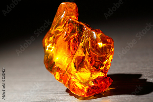 Bright transparent piece of amber on a black background. Sun stone. Petrified resin of ancient fossil trees. Material for jewelers. Natural mineral. Digging. Crystal. Overflow colors