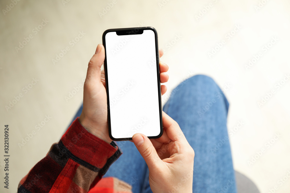 Woman in shirt and jeans holding phone with empty screen