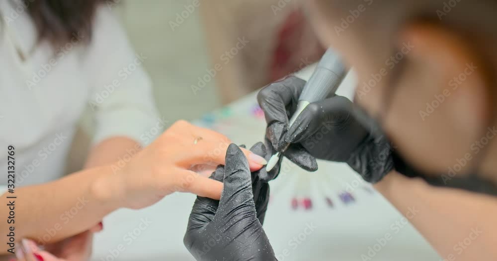 Manicurist removes polish with a cutter from the nails of the client. Close-up. Manicurist removes polish with a cutter from the nails of the client. Close-up.
