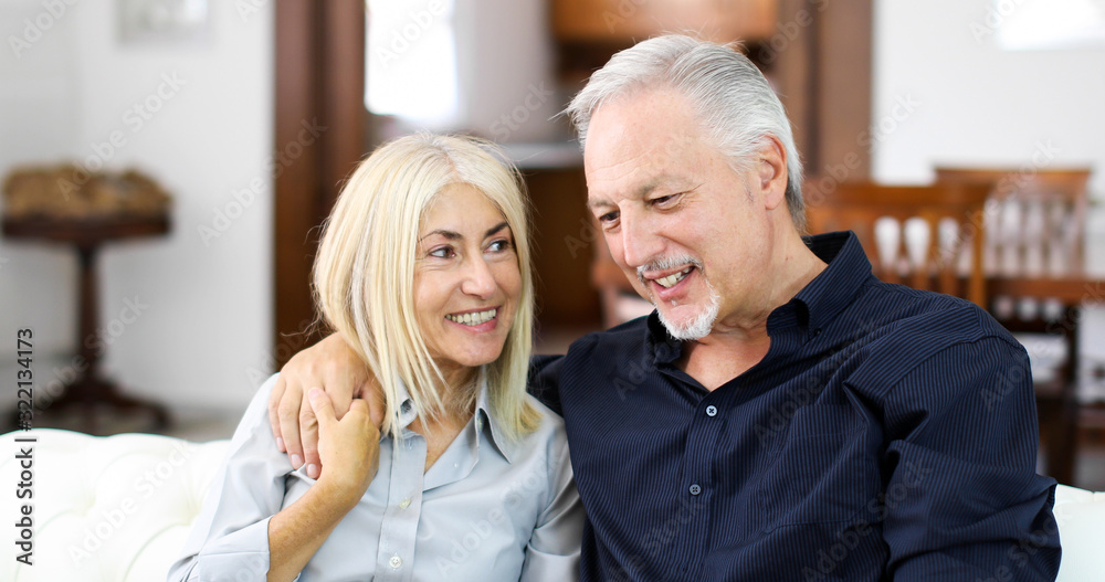 Senior couple relaxing on a sofa and talking together Senior couple relaxing on a sofa and talking together