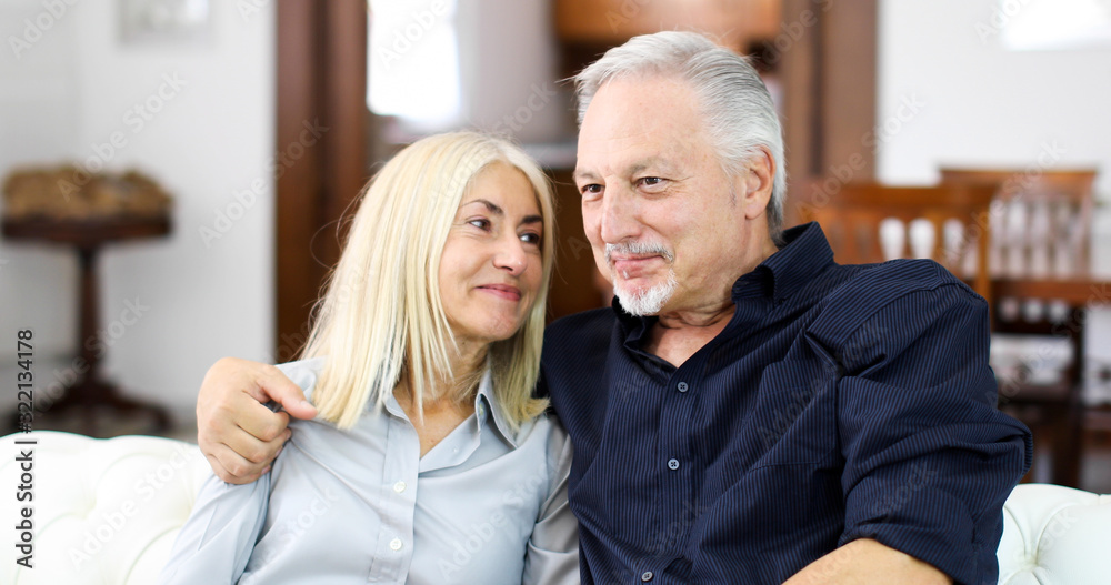 Senior couple relaxing on a sofa and talking together Senior couple relaxing on a sofa and talking together