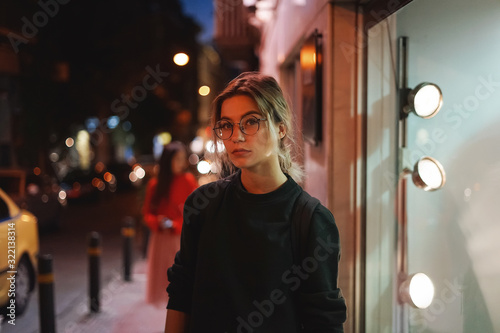 Modern pretty woman in glasses, city lights. Close up portrait in night city