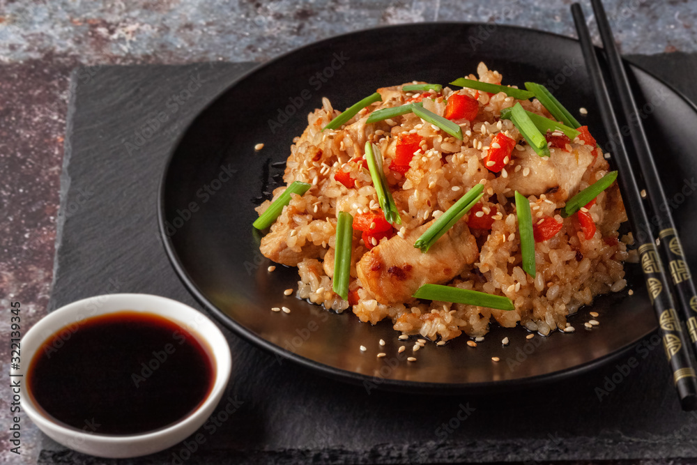 Tori chahan fried Japanese rice with vegetables and chicken in soy sauce in a black plate on a serving board Tori chahan fried Japanese rice with vegetables and chicken in soy sauce in a black plate on a serving board