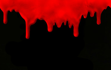 Streaks of red paint on a black background. Red paint leaking down on black. Halloween concept - dripping blood. Blood drops on black background.