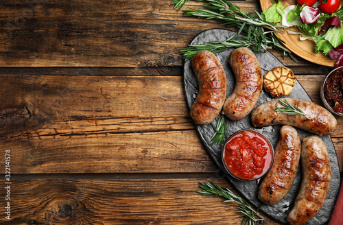 Tasty grilled sausages served on wooden table, flat lay. Space for text