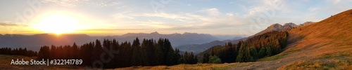 Breathtaking panoramic shot of beautiful steep hills and forest with the sunrise in the background photo