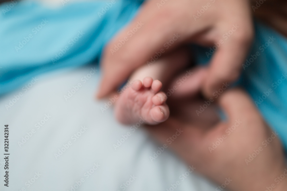feet of a newborn child in the hands of parents.  Parental care, parental love