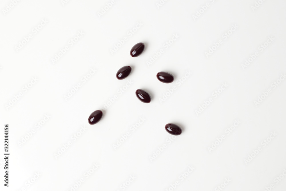 Astaxanthin capsules scattered on a white background. Top view. Astaxanthin capsules scattered on a white background. Top view.