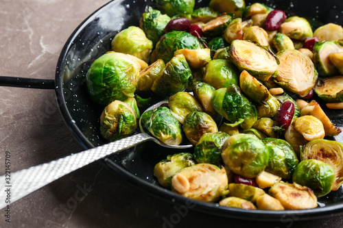 Delicious roasted brussels sprouts with red beans and peanuts on marble table, closeup