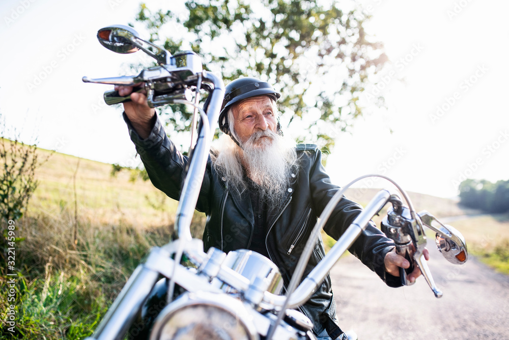 A senior man traveller with motorbike in countryside.