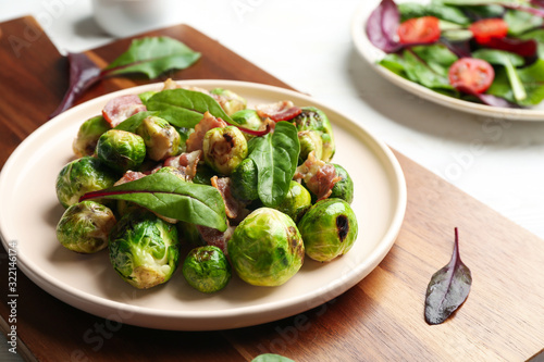Delicious Brussels sprouts with bacon on wooden board, closeup