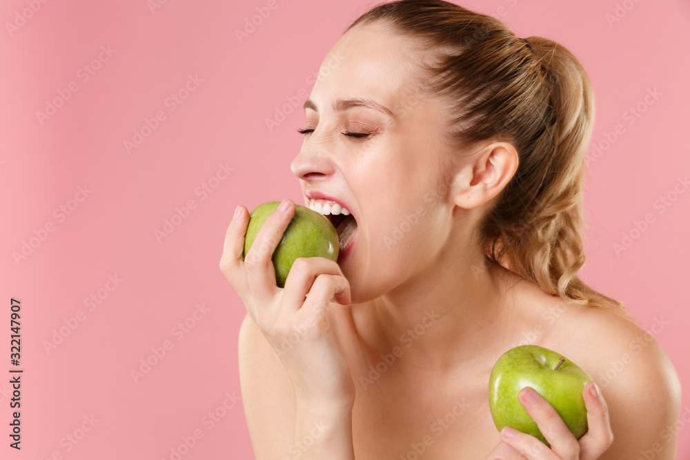 Close up blonde half naked woman 20s perfect skin nude make up hold apple isolated on pastel pink wall background studio portrait. Skin care healthcare cosmetic procedures concept. Mock up copy space. Close up blonde half naked woman 20s perfect skin nude make up hold apple isolated on pastel pink wall background studio portrait. Skin care healthcare cosmetic procedures concept. Mock up copy space.