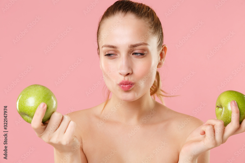 Close up blonde half naked woman 20s perfect skin nude make up hold apple isolated on pastel pink wall background studio portrait. Skin care healthcare cosmetic procedures concept. Mock up copy space. Close up blonde half naked woman 20s perfect skin nude make up hold apple isolated on pastel pink wall background studio portrait. Skin care healthcare cosmetic procedures concept. Mock up copy space.