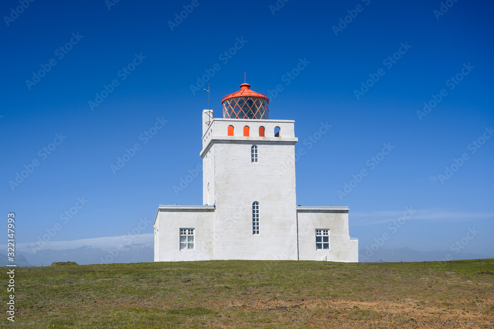 Dyrholaey Lighthouse in sunny day against blue sky