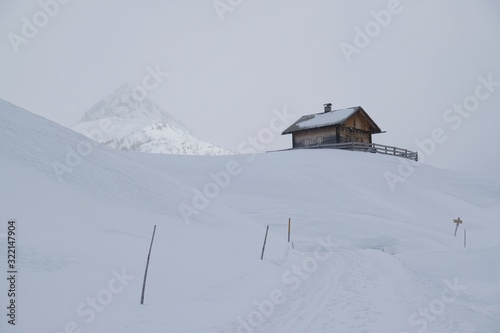 Beautiful view of lonely small wooden house in snowy mountains in foggy winter day, when all around is white. Around Alpe di Nemes refuge in Sexten Dolomites, South Tyrol, Italy © Iwona