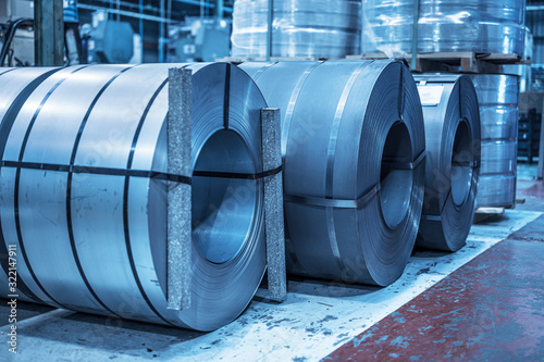 Industrial background. Big size steel coil stored inside industrial warehouse, blue toned image . photo