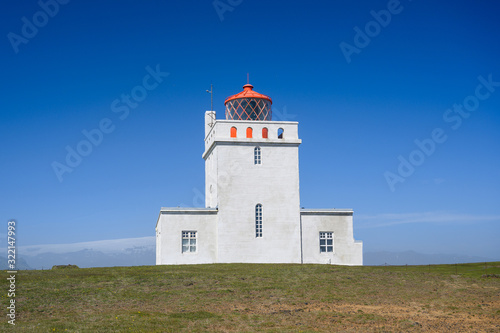 Dyrholaey Lighthouse in sunny day against blue sky