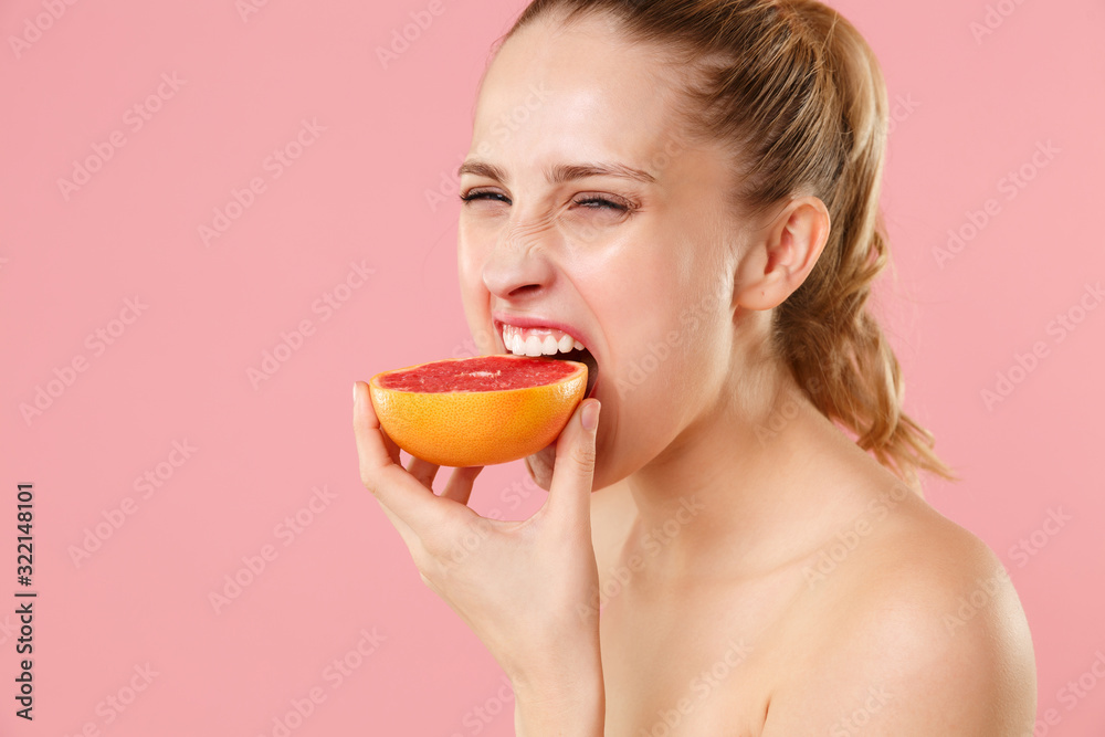 Close up blonde half naked woman 20s perfect skin nude make up blue eyes hold in hand grapefruit isolated on pastel pink background studio portrait. Skin care healthcare cosmetic procedures concept. Close up blonde half naked woman 20s perfect skin nude make up blue eyes hold in hand grapefruit isolated on pastel pink background studio portrait. Skin care healthcare cosmetic procedures concept.