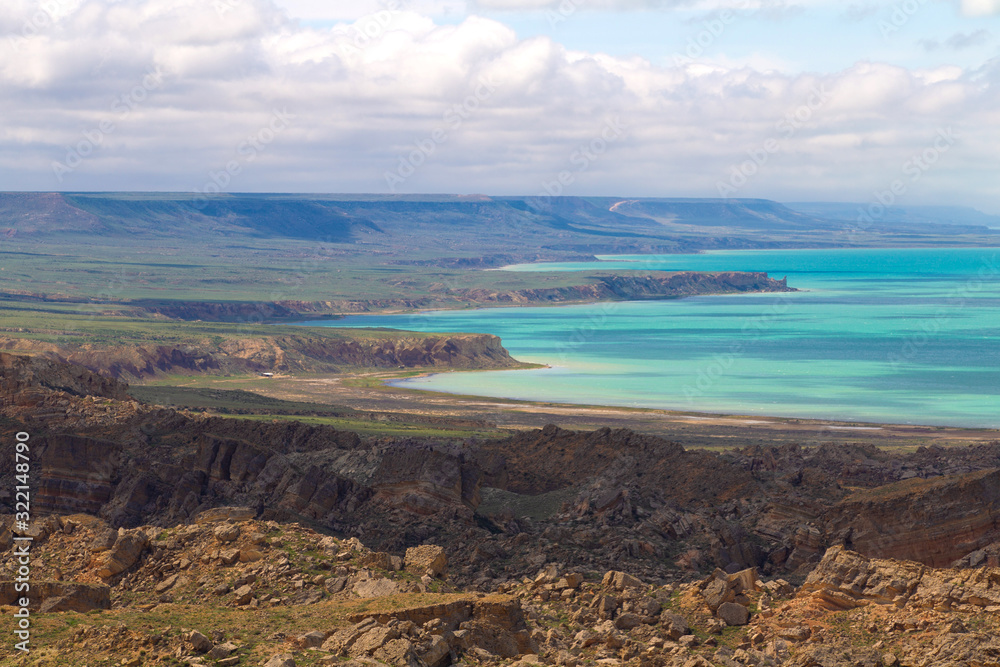 Turquoise sea with a rocky beach and white clouds in summer