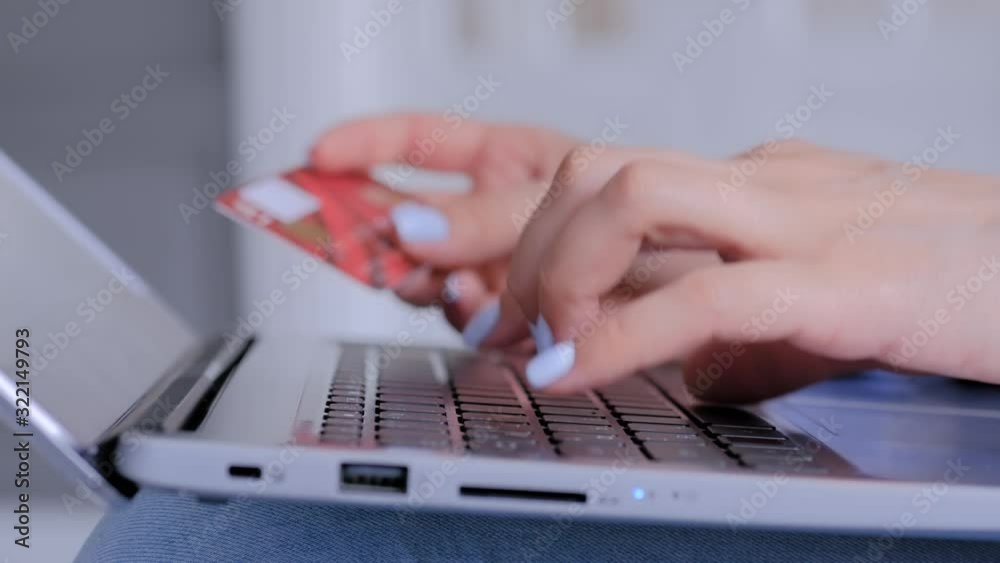 Woman using laptop computer keyboard, holding credit card, buying goods or ordering online - close up side view. Online shopping, e-commerce, sale, consumerism, electronic payment, technology concept Woman using laptop computer keyboard, holding credit card, buying goods or ordering online - close up side view. Online shopping, e-commerce, sale, consumerism, electronic payment, technology concept
