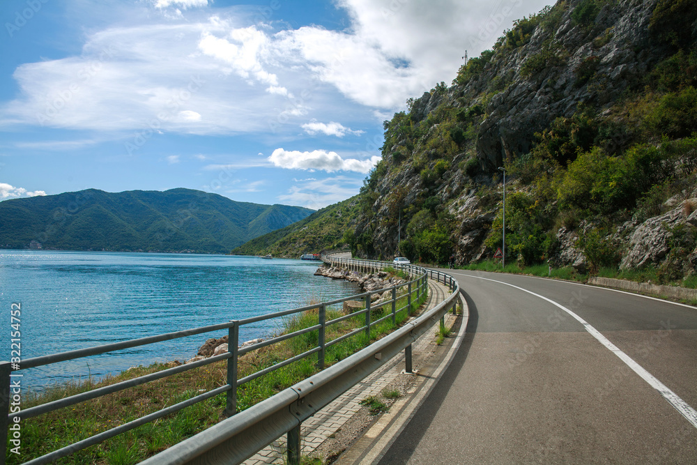 Fototapeta premium Asphalt road along sea bay and mountains on blue sky, Europe, Montenegro, Kotor