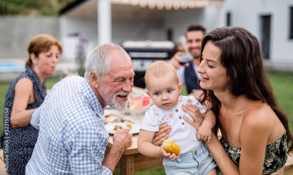 Portrait of extended family sitting at table outdoors on garden barbecue. Portrait of extended family sitting at table outdoors on garden barbecue.