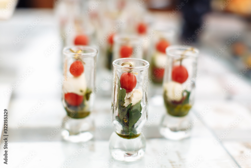 Canapes of tomatoes and cheese in a glass with pesto sauce on a blurry background