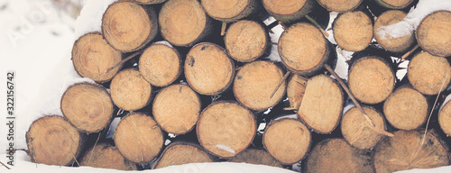 Pile of wooden logs under snow in winter  background  selective focus  banner