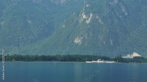 Old steam boat ship on Lake Geneva. Swiss Flag. Lac Leman, Switzerland summer tourism destination, 4k. Turquoise blue water.