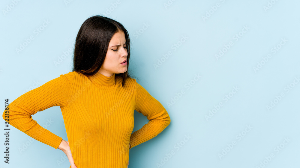 Young caucasian woman isolated on blue background suffering a back pain. Young caucasian woman isolated on blue background suffering a back pain.