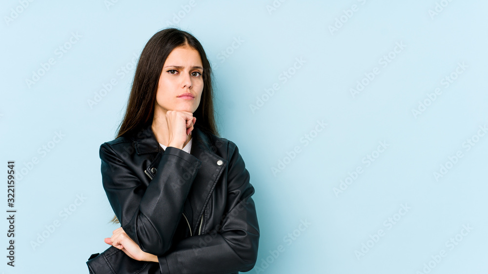 Young caucasian woman isolated on blue background suspicious, uncertain, examining you. Young caucasian woman isolated on blue background suspicious, uncertain, examining you.