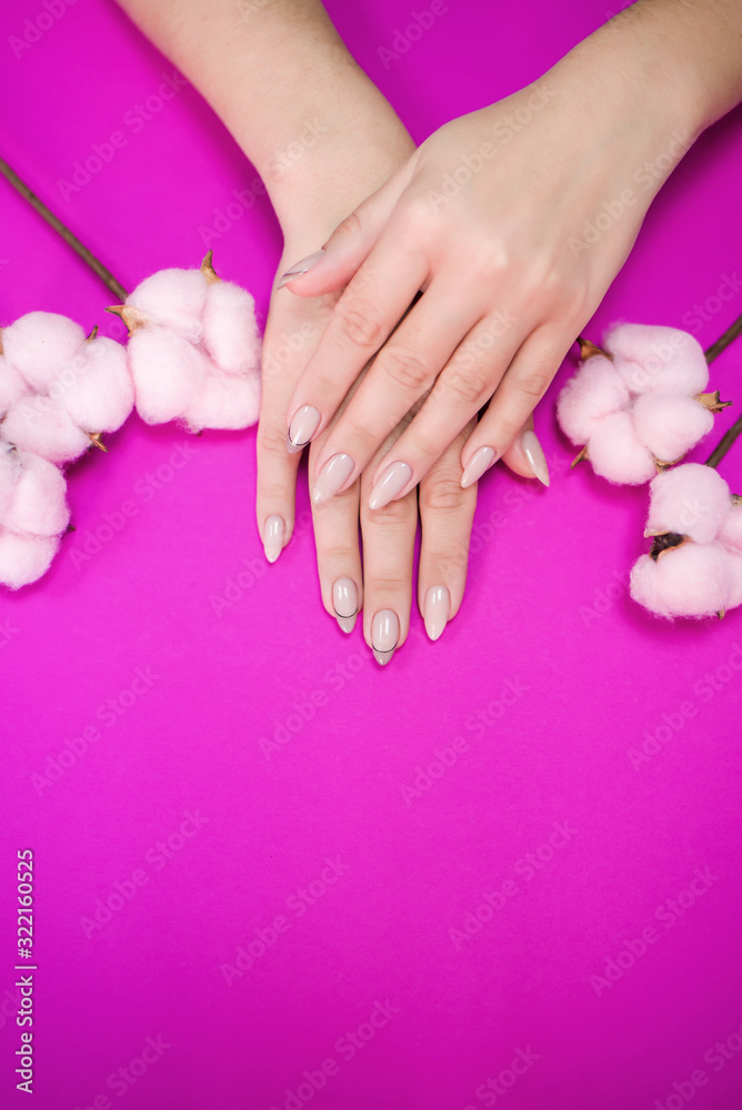 Beautiful women's manicure in delicate tones, on a bright background with gently pink cotton.