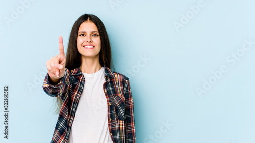 Young caucasian woman isolated on blue background showing number one with finger.