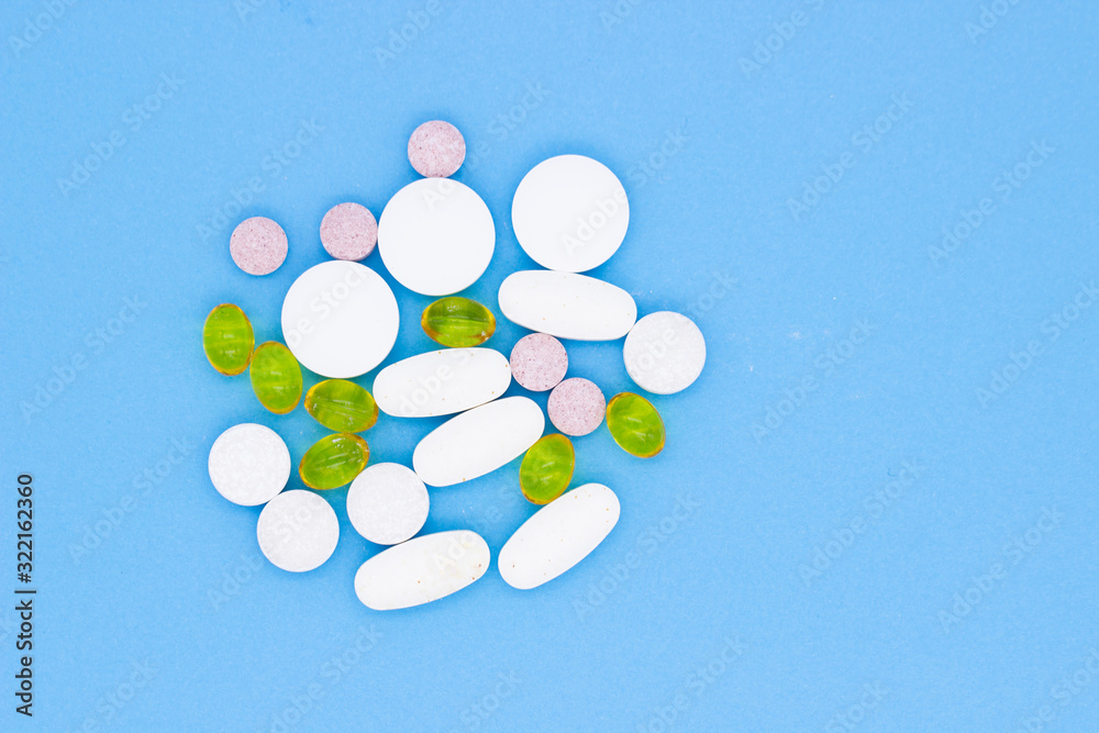 Different vitamins, pills and capsules on a blue background.