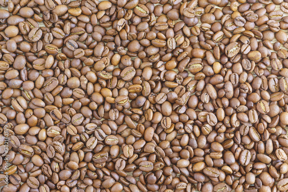 Brown Arabica coffee beans are scattered evenly on the table Brown Arabica coffee beans are scattered evenly on the table