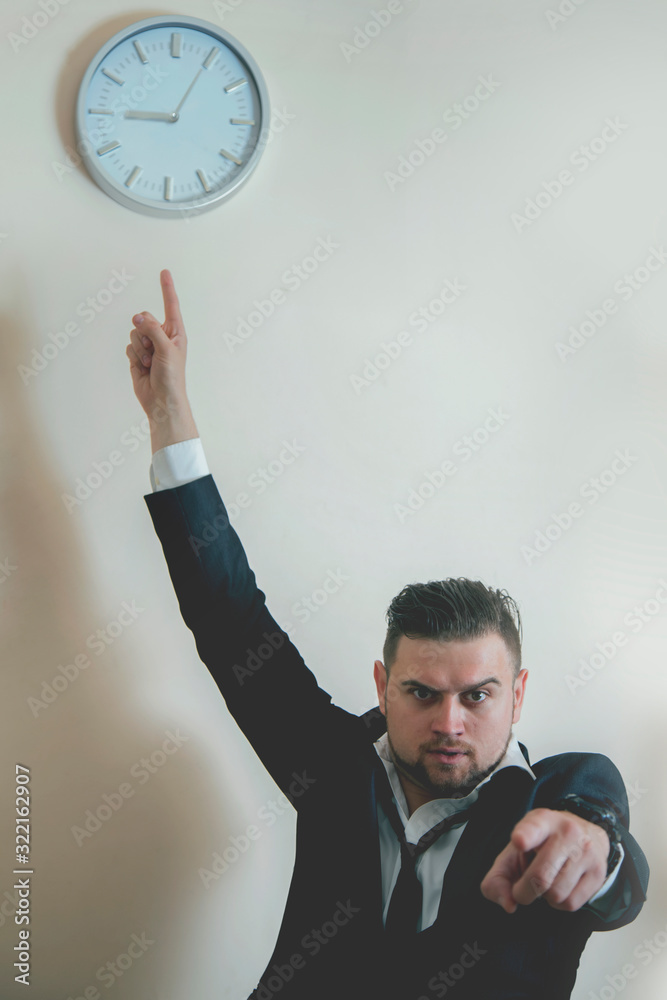 You're late! Angry businessman is pointing at clock suggesting you are late for work. You're late! Angry businessman is pointing at clock suggesting you are late for work.